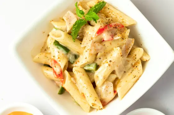 A bowl of pasta in a creamy sauce with cherry tomatoes and grated cheese