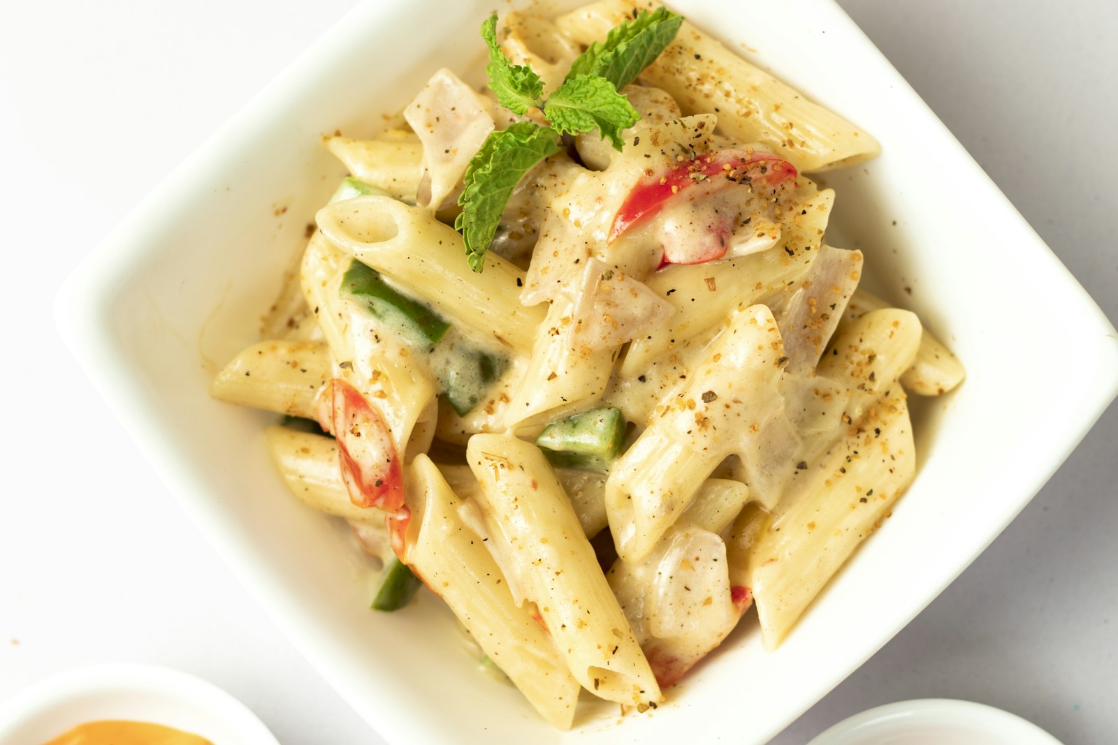 A bowl of pasta in a creamy sauce with cherry tomatoes and grated cheese