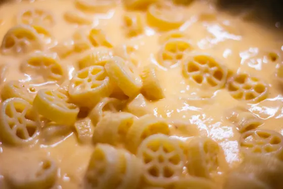 Wagon wheel pasta in a smooth, pale orange cheese sauce, photographed close up