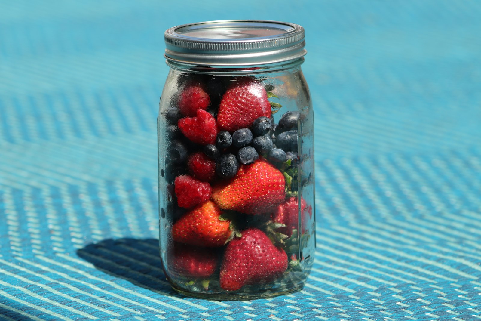 A jar of overnight oats topped with fresh berries on a light surface